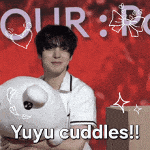 a man holding a stuffed animal in front of a red background that says our yuyu cuddles