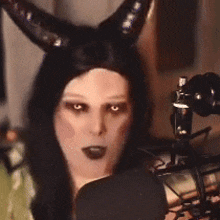 a woman wearing a horned hat is talking into a microphone .