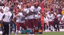a group of football players are celebrating a touchdown in front of a crowd