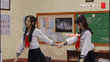 two girls are holding hands in front of a blackboard that says free fire