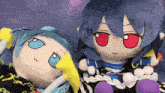 two stuffed dolls with blue hair and red eyes are laying on a checkered table