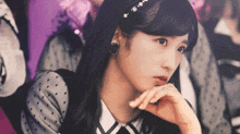 a girl wearing a headband and earrings is looking at the camera