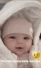 a baby wrapped in a white blanket with a smiley face on the bottom