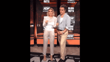 a man and a woman standing in front of a wall that says aew
