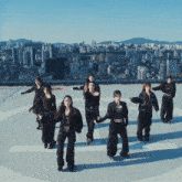 a group of young women are dancing on a rooftop with a city in the background