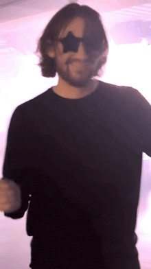 a man wearing sunglasses and a black shirt is smiling