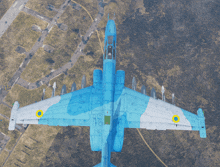 an aerial view of a blue and white fighter jet with a yellow circle on the tail