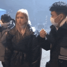 a man wearing a mask talks to a woman