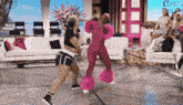 a woman in a pink outfit is dancing in front of a couch