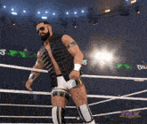 a man in a black vest and white shorts is in a wrestling ring