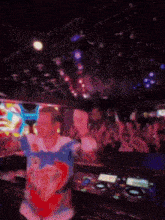 a man wearing a shirt that says ' i love you ' is dancing in front of a crowd