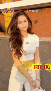 a woman wearing a white crop top and white pants is standing in front of a yellow sign that says rit 06 on it