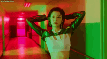 a woman in a crop top is standing in a hallway with a green light behind her