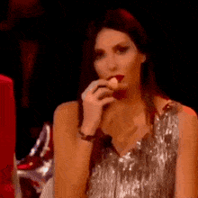 a woman in a silver dress is eating a piece of cake