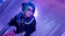 a girl with blue hair and glasses stands in front of a purple wall