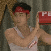 a man wearing a bandana and a name tag that says brent holds a red can