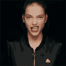 a woman wearing a black jacket is making a funny face .