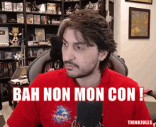 a man wearing a red shirt with the words bah non mon con written on it