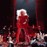 a woman in a red dress is singing into a microphone in front of a crowd