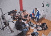 a group of people are sitting in a messy room with a sign on the wall that says 3