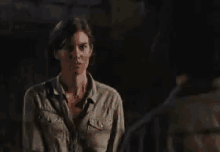 a woman is standing in front of a man in a dark room .