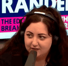 a woman wearing headphones is talking into a microphone in front of a sign that says " the ed break "