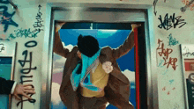 a man is standing in an elevator with graffiti on the walls .