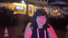 a woman with a lanyard around her neck smiles in front of a blurred background