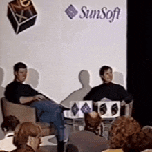 a group of people sit in front of a sign that says sunsoft