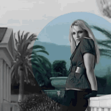 a woman is standing on a balcony in front of a palm tree