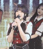 a girl singing into a microphone while standing next to another girl