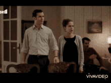 a man and a woman are standing in a living room with the word vivavideo on the bottom right