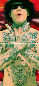 a man with a lot of tattoos on his arms and chest is wearing sunglasses and a hat