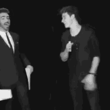 two men are standing next to each other in a black and white photo .