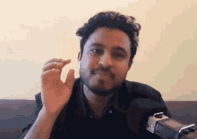 a man with a beard is sitting in front of a microphone and holding something in his hand