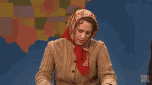a woman wearing a scarf and a sweater is making a funny face .