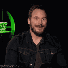 a man wearing a denim jacket is laughing in front of a star wars sign