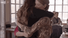 two women hugging in front of a sign that says an7