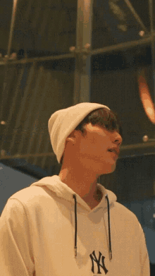 a man wearing a white ny hat and a white hoodie
