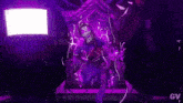 a purple skeleton is standing in a dark room with a purple light behind him .