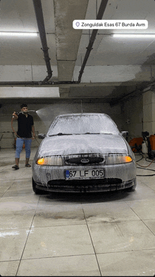 a man is washing a car with a license plate that reads 67 lf 005