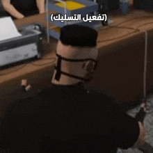 a man wearing glasses and a mask is standing in front of a desk with arabic writing on it ..