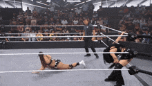 two women are wrestling in a wrestling ring with a referee watching
