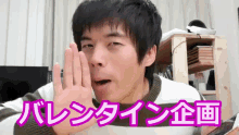 a man covering his mouth with his hand in front of a sign that says ' valentine ' on it