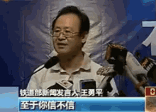 a man wearing glasses is speaking into a microphone with chinese writing on the screen
