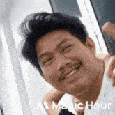 a man with a mustache is smiling in front of a magic hour sign
