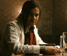 a man with long hair is sitting at a bar with a glass of beer