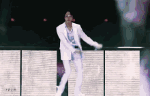 a man in a white suit is dancing in front of a screen that says spjm on it