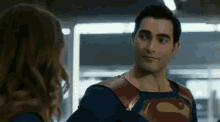a man in a superman costume is talking to a woman in a red and blue superhero costume .