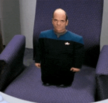 a man in a star trek uniform is kneeling down in a chair